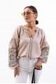 Women's embroidered blouse light beige with smooth flowers on the sleeves. Spring.